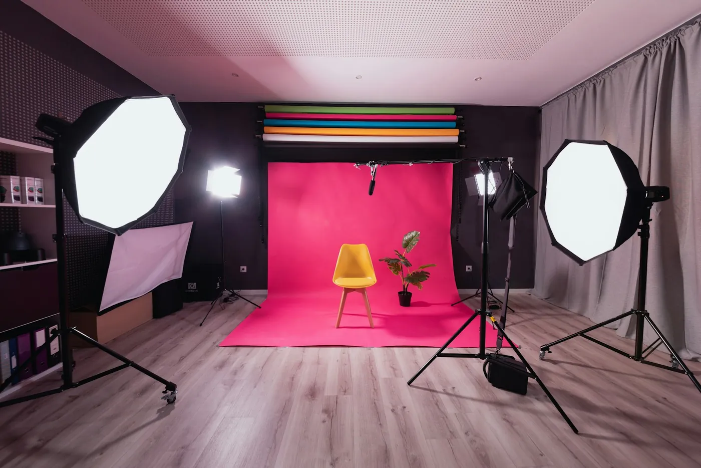 A photo studio with a pink backdrop and a yellow chair