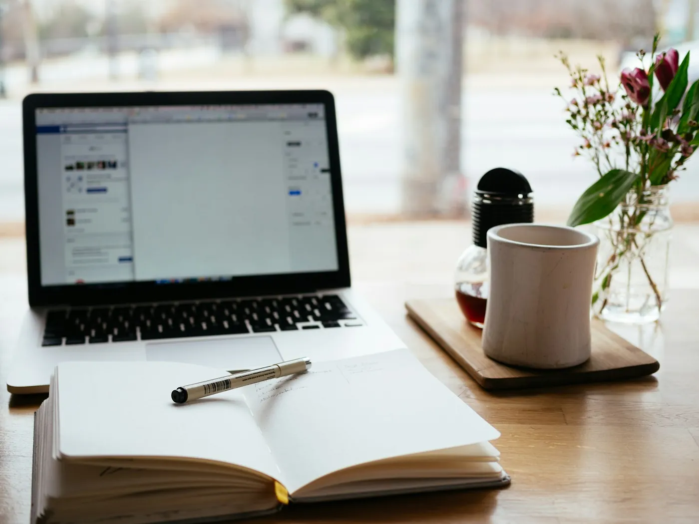 A laptop open beside a notebook on a desk