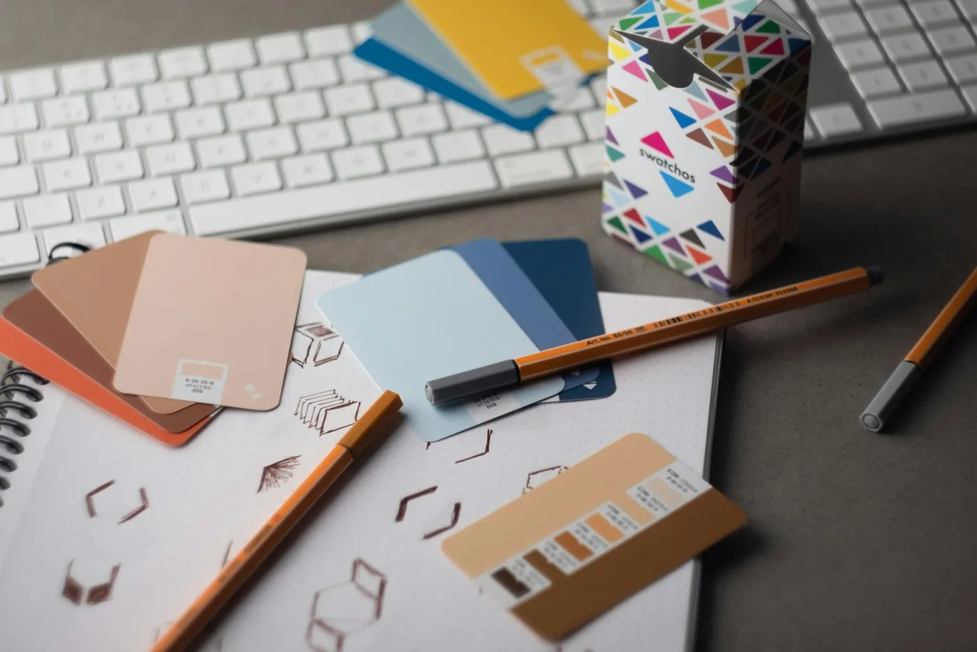 A desk with a keyboard, pencils and colour samples
