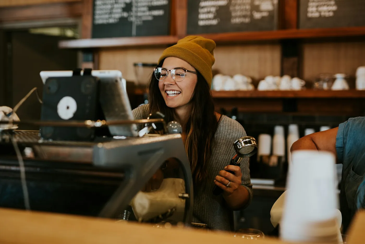A smiling barista holding a portafilter